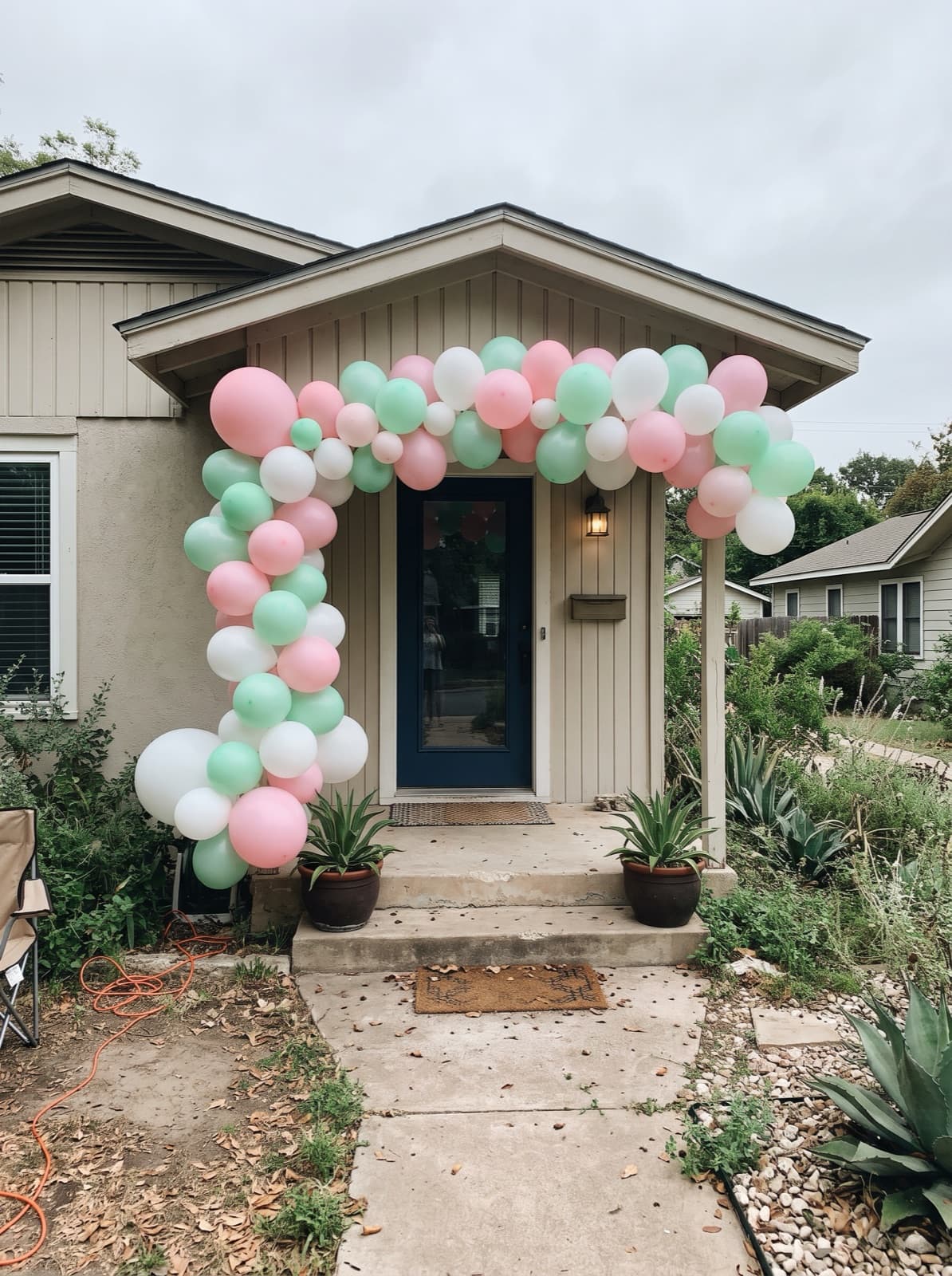 Pastel balloon arch over the front door of a bungalow porch