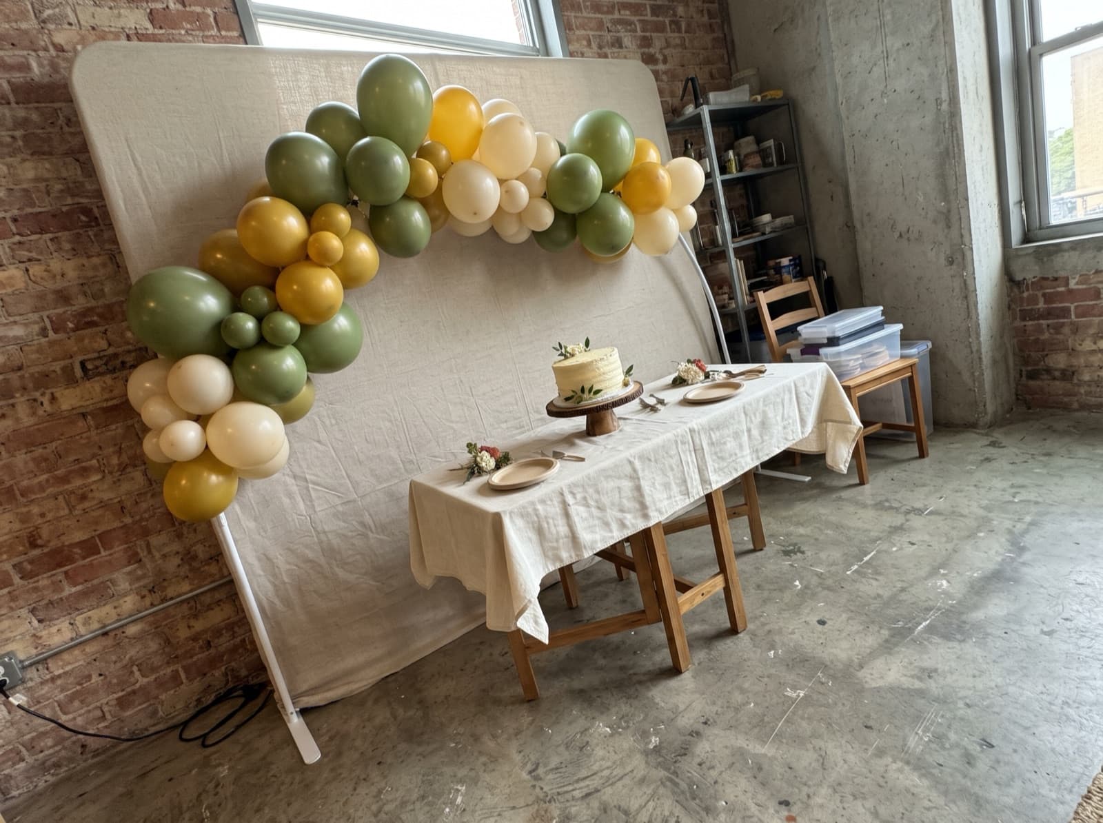 Half balloon arch in olive, mustard and cream over a cake table